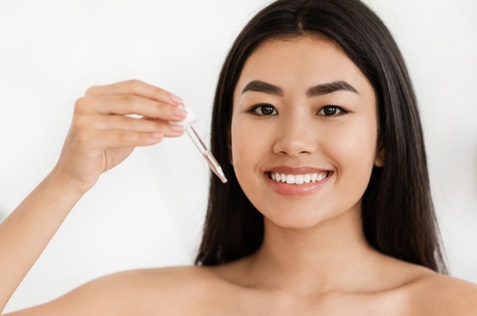 Perempuan menggunakan serum untuk kulit berjerawat